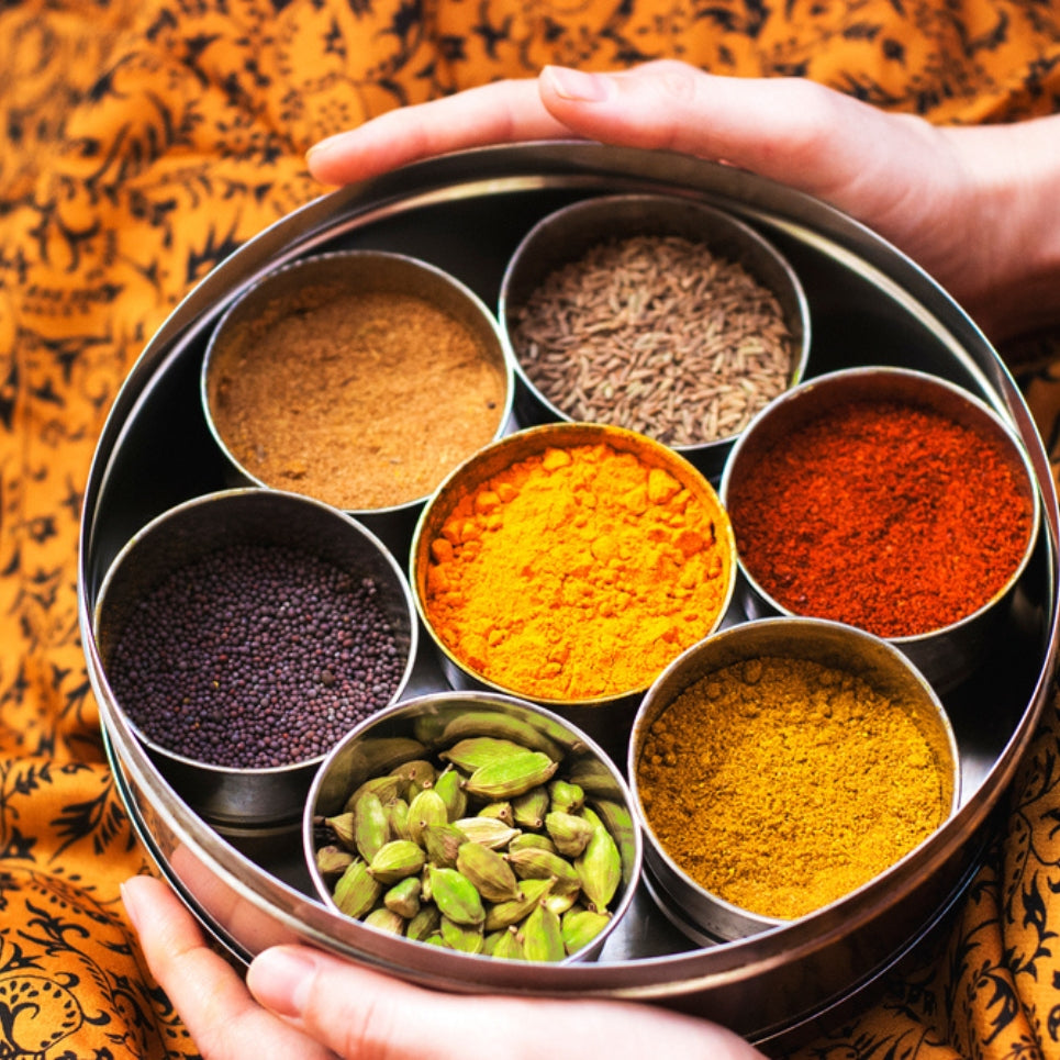 Open masala dabba showing 7 individual spice containers with 2 spoons