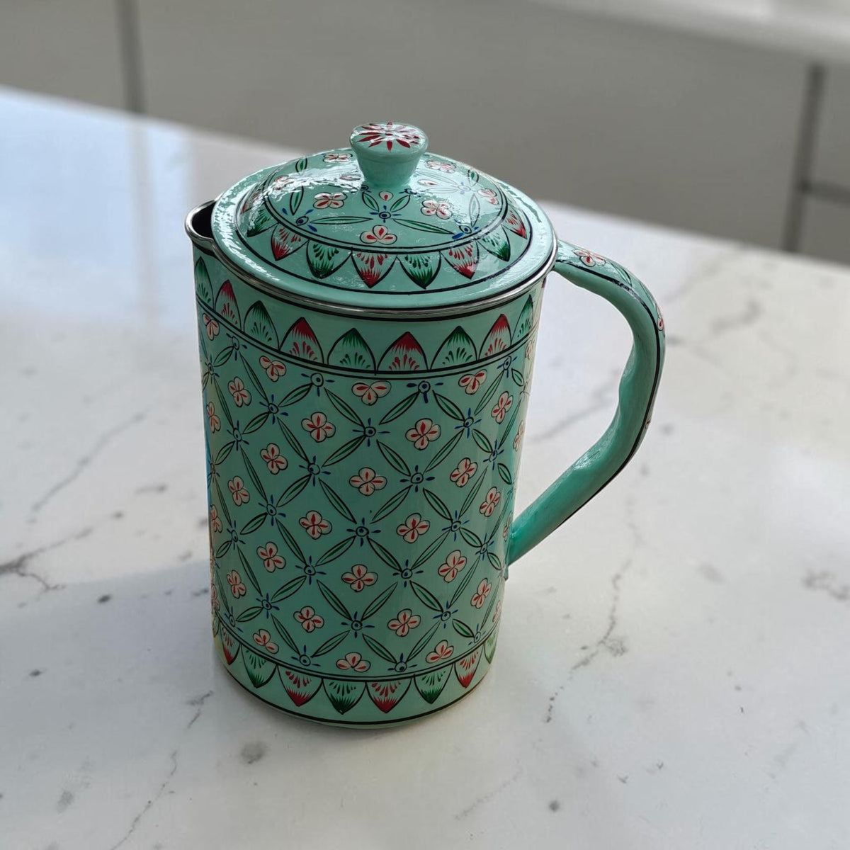 Hand-painted geometric floral water jug in light teal on kitchen counter